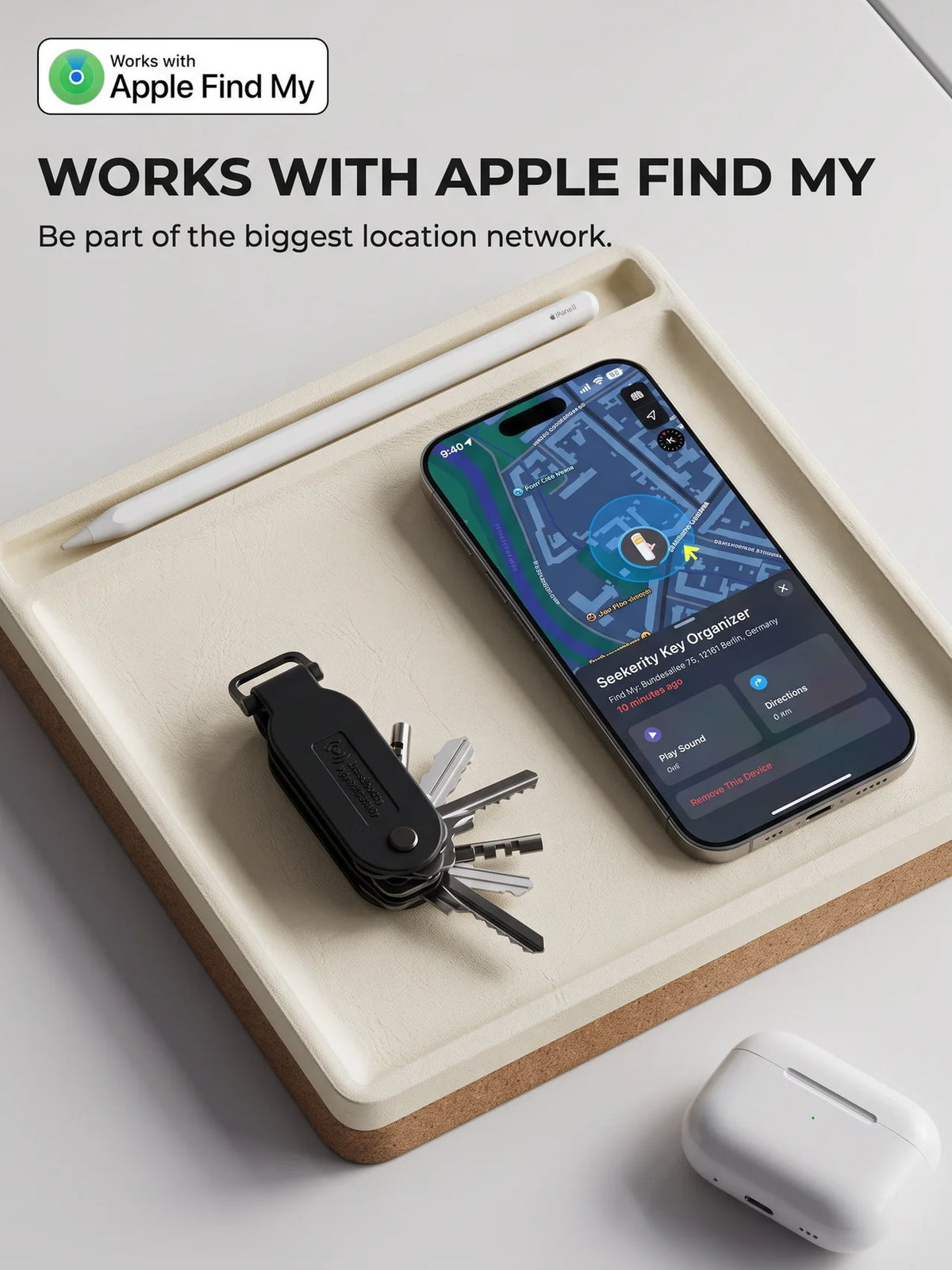Key organizer on a tray next to an iPhone showing its location on the Apple Find My network